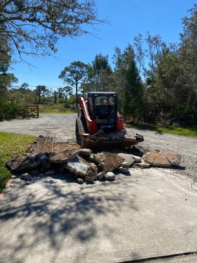 Track loader hauling concrete debris from a driveway