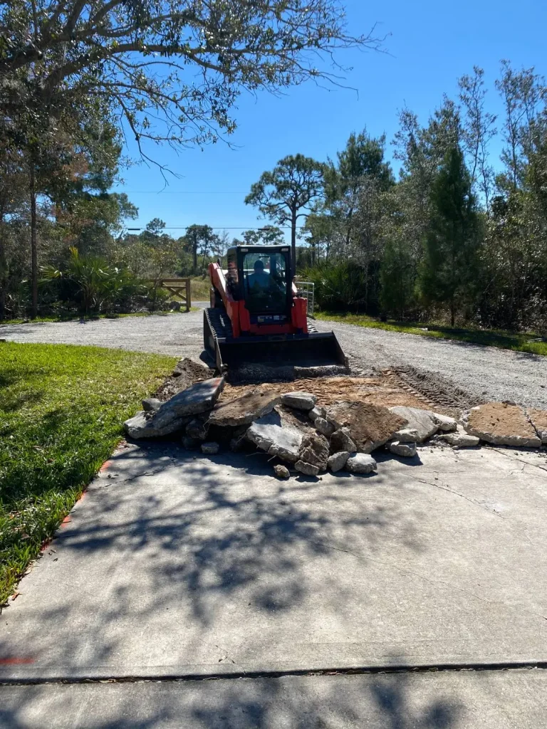 Track loader removing an old concrete driveway