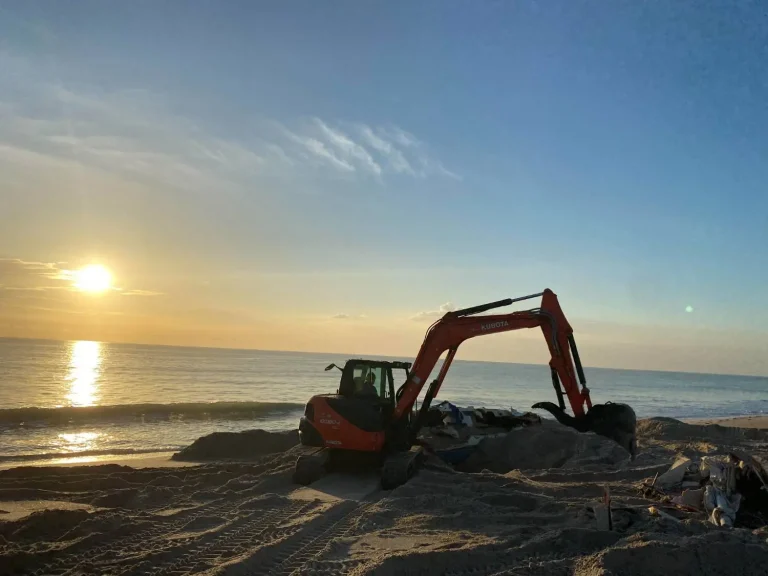 Excavator working on the beach at sunrise
