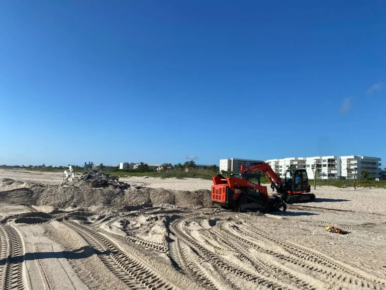 Track loader on the beach near oceanfront condos