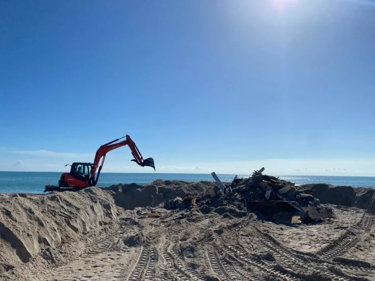 Excavator working on a beach dune by the ocean