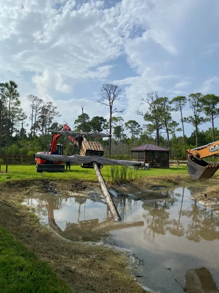 Excavator digging a pond on a wooded lot