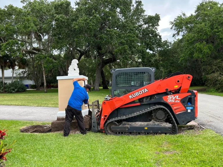 Crew member working beside a Kubota track loader at an estate entrance