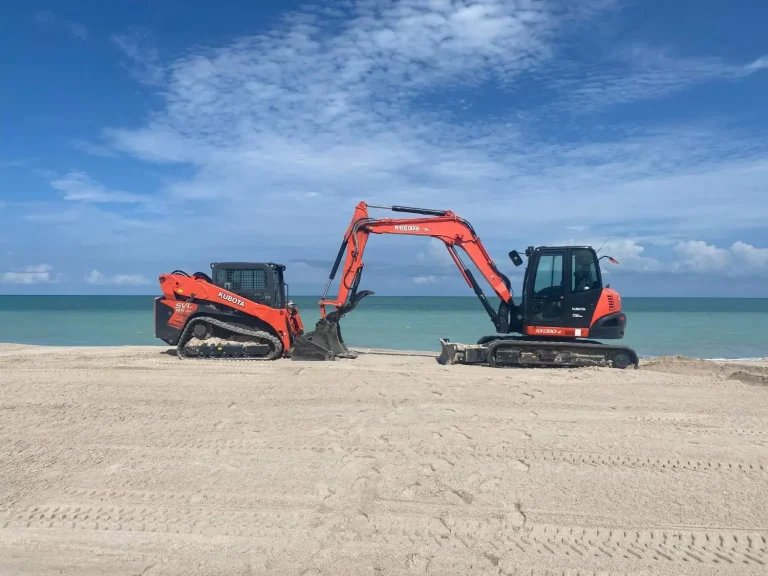 Track loader and mini excavator parked on a sandy beach