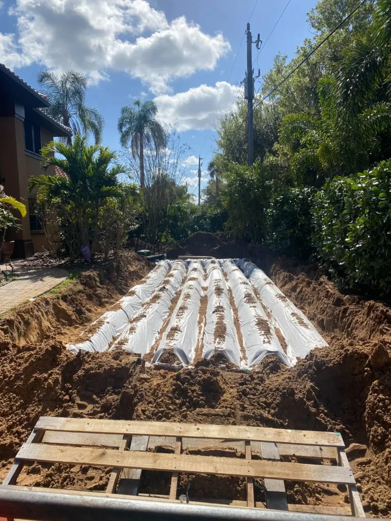 Drainfield chambers laid on a sand bed beside a house