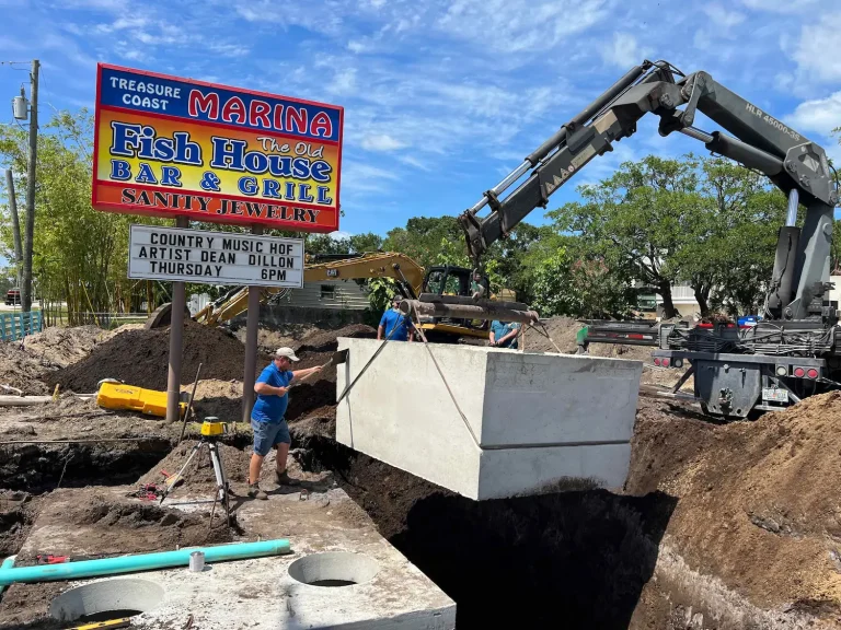 Crane setting a commercial septic tank beside a restaurant