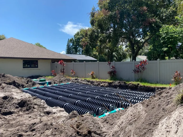 Drainfield chambers laid in a fenced backyard beside a home
