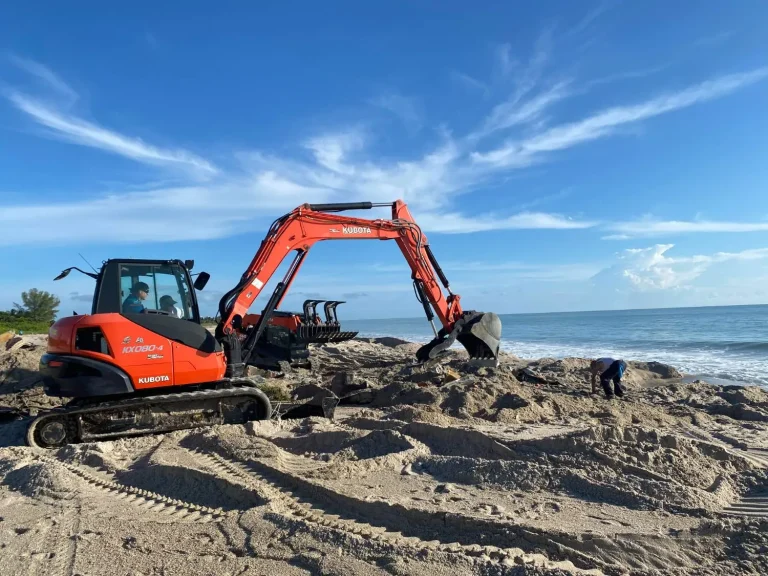 Excavator working on a beach at sunrise